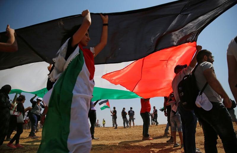 Young people hold large Palestinian flag