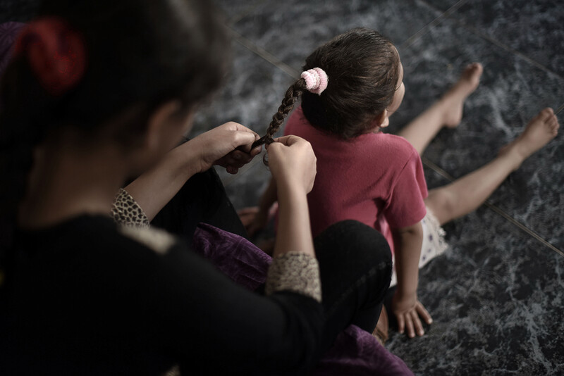 Older girl braids smaller girl's hair