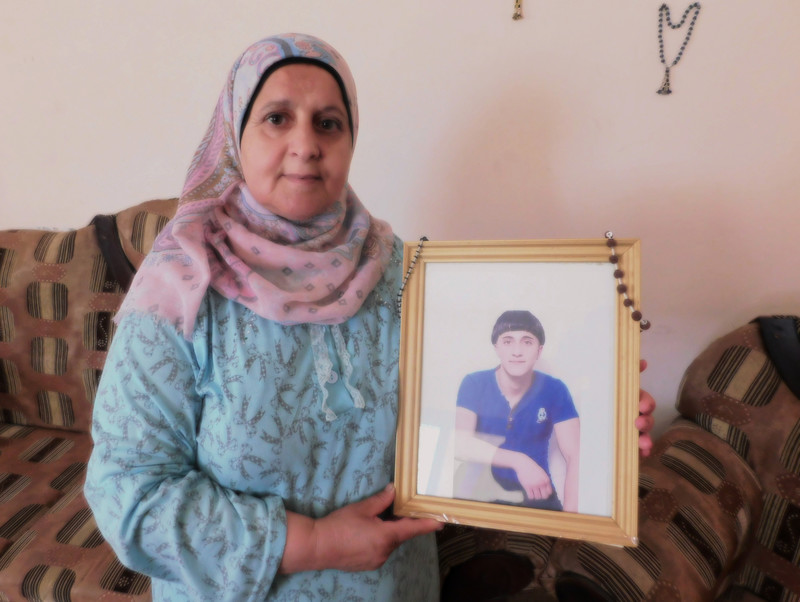 Woman holds framed photograph of teenage boy
