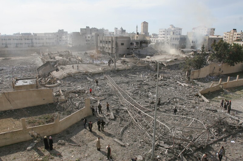 Landscape view of neighborhood flattened by bombing and dust rising up from ruins