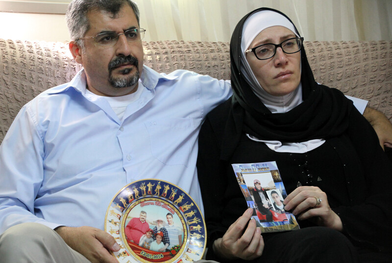 Man and woman sit on couch and hold family photographs
