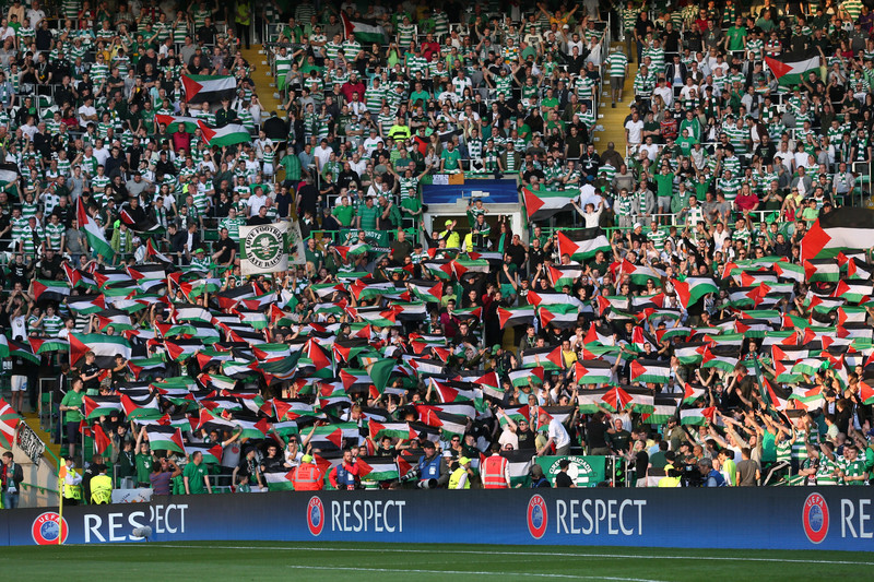 Dozens of football spectators hold up Palestinian flags in full stadium
