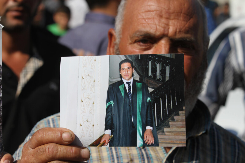 Older man holds photograph of young man wearing graduation gown