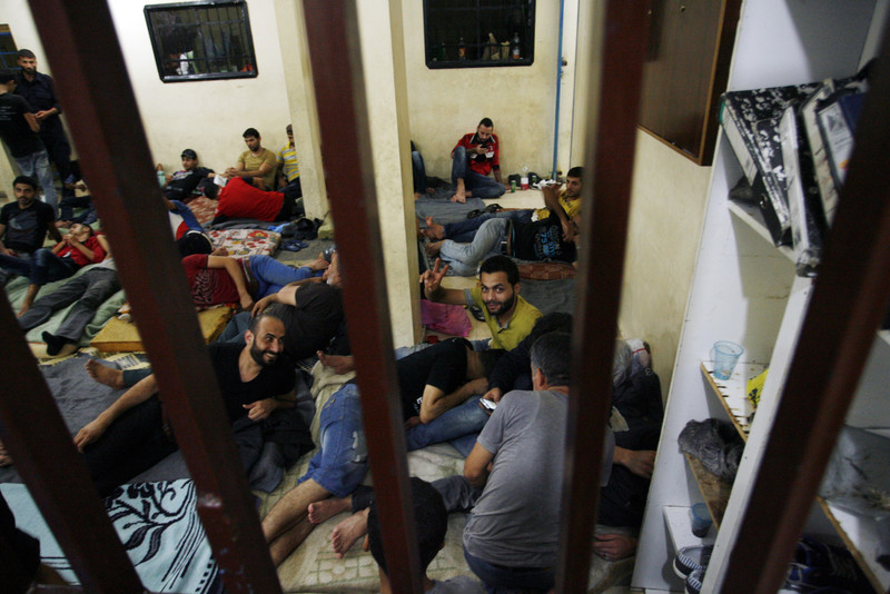 Group of men lounge on floor of detention cell