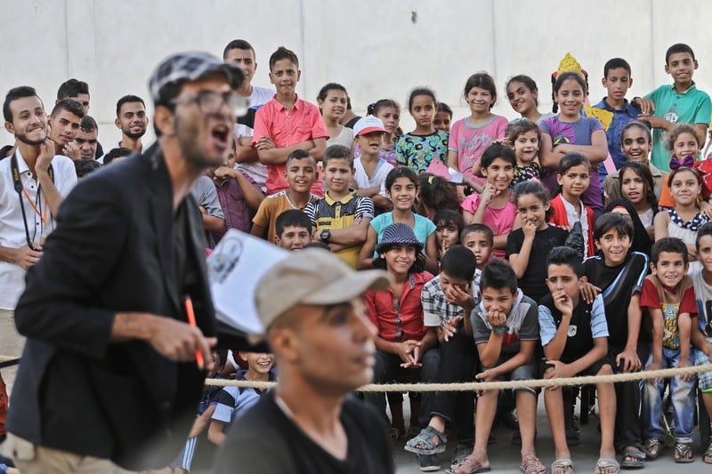 Crowd of boys and girls watch actors perform in street