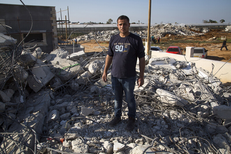 Young man stands on rubble of demolished home