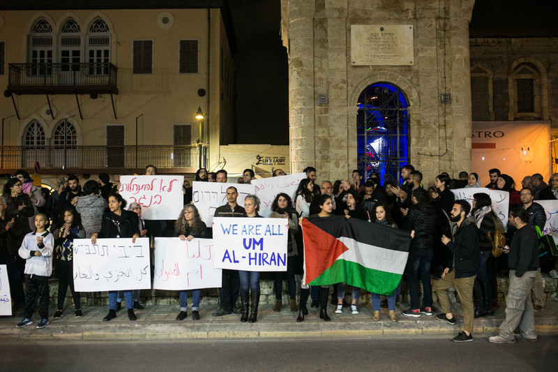 Protesters hold Palestinian flag and signs