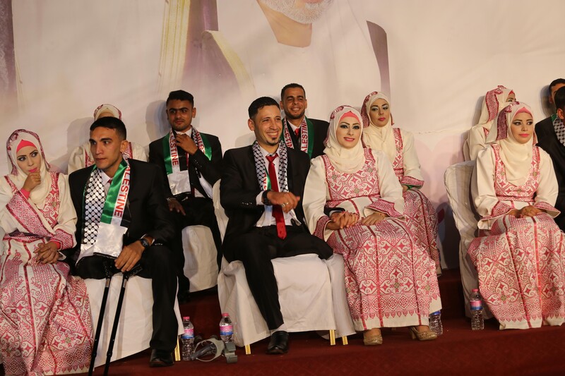 Young women wearing traditional embroidered dresses sit next to young men wearing suits