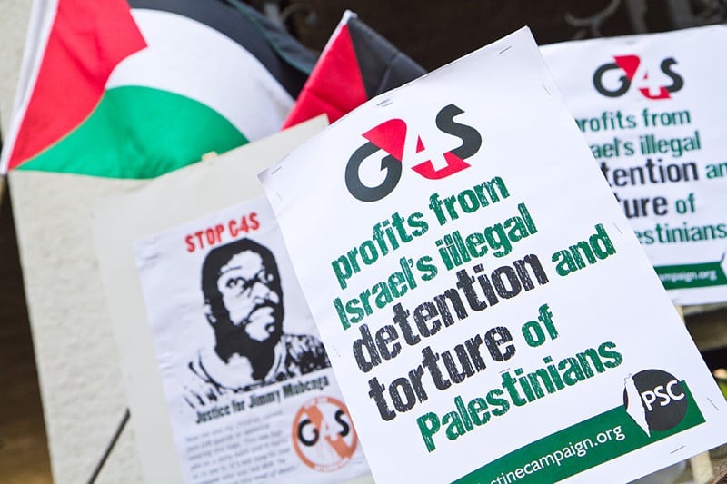 Protest signs read: G4S profits from Israel's illegal detention and torture of Palestinians