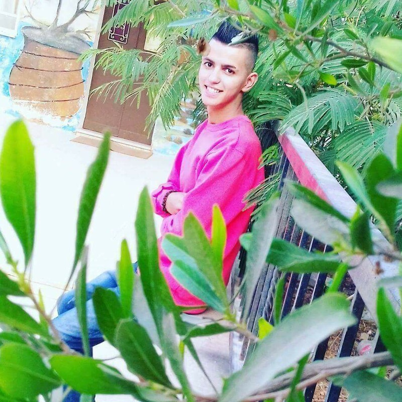 Smiling youth sits on bench amid foliage