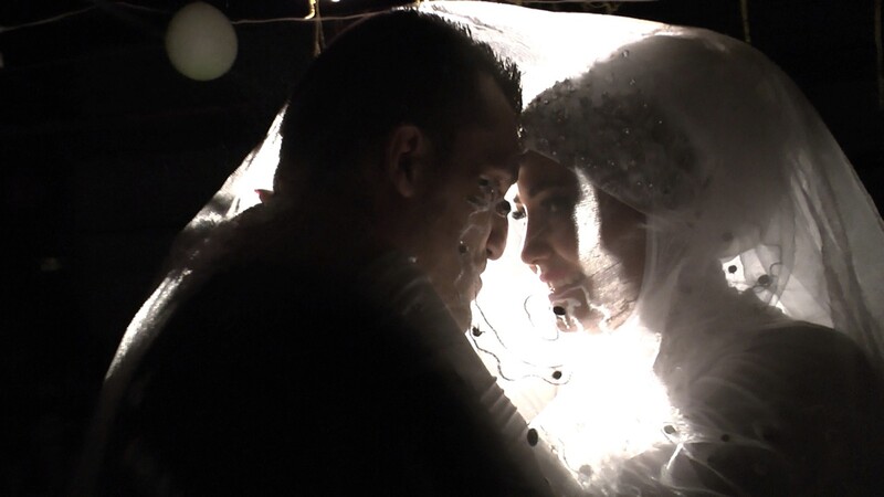 Smiling bride and groom seen from the chest up lean in towards each other