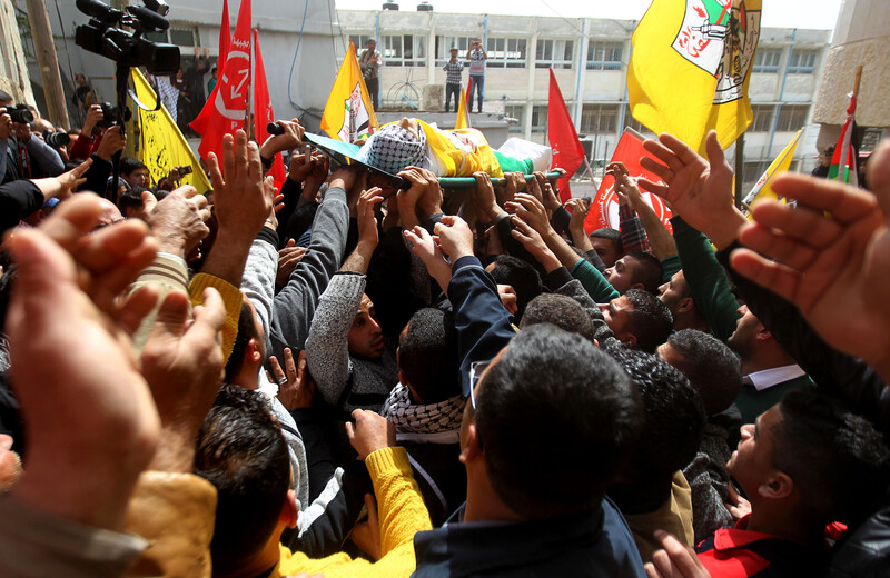 Photo shows hands reaching towards Murad Abu Ghazi as his body is carried during his funeral procession