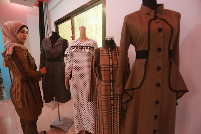 Young woman stands among four dress forms featuring her garments