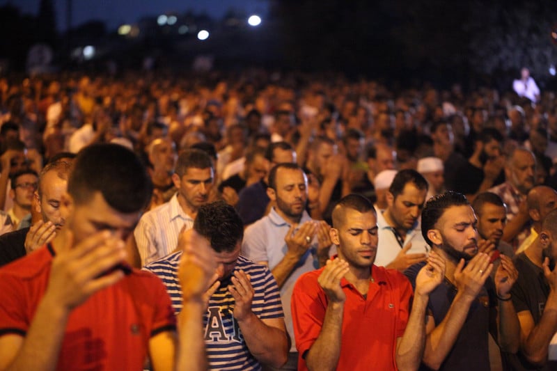 Hundreds of men pray outside at night