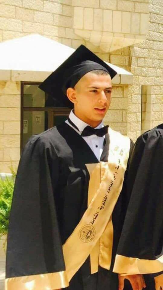 Photo shows young man wearing graduation cap and gown from waist up