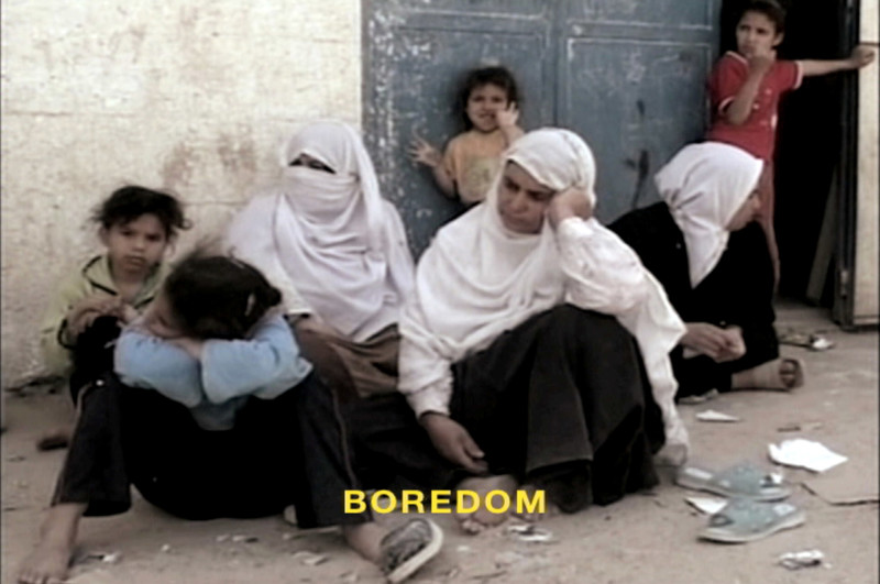 Three women sit on ground, accompanied by several children, with subtitle reading BOREDOM