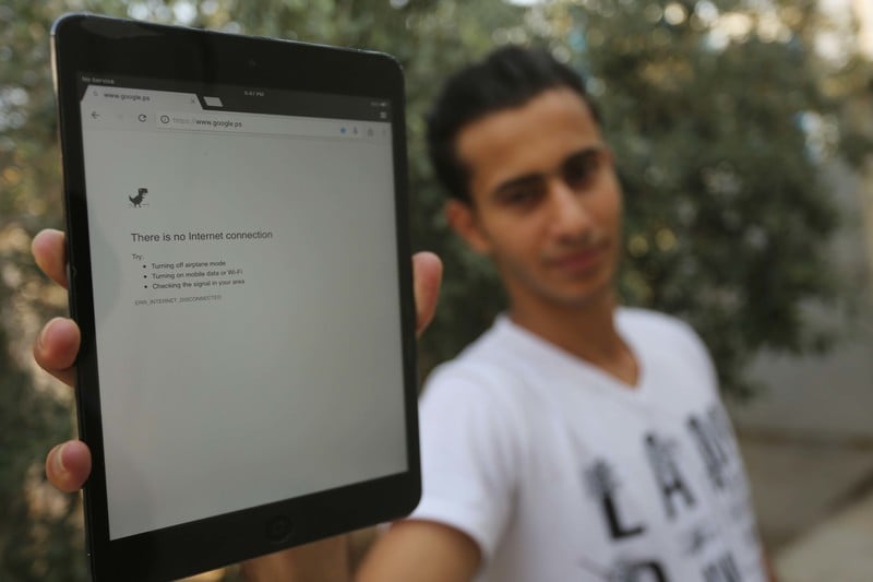 Young man holds up electronic tablet showing an Internet browser error stating, There is no Internet connection
