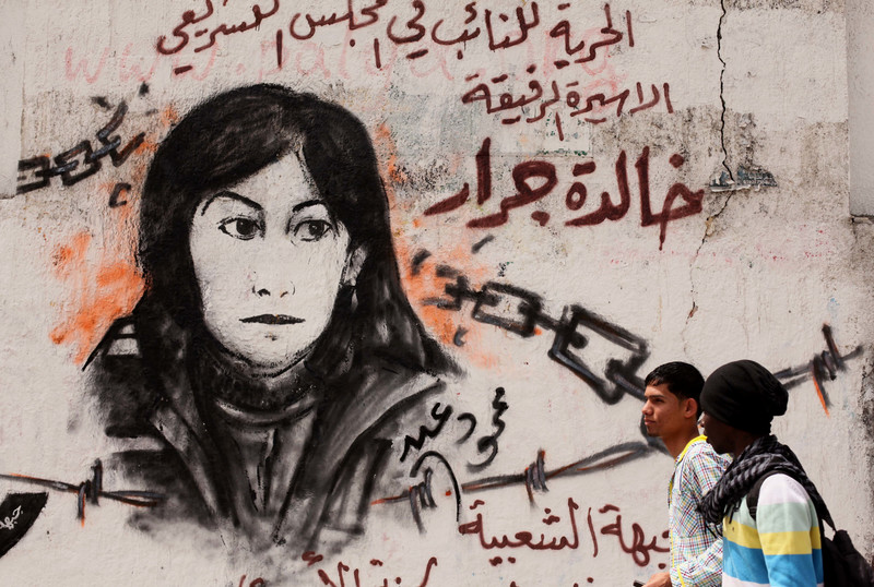 Two Palestinian children walk past a mural of Khalida Jarrar, a member of the Popular Front for the Liberation of Palestine, who remains jailed in Israeli prisons. 