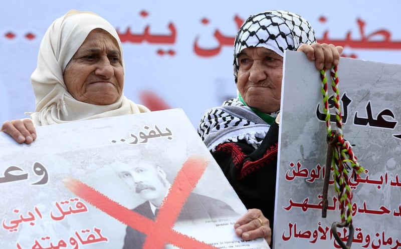 Elderly women hold up posters protesting the Balfour declaration