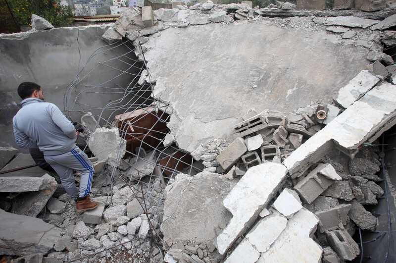 Man stands next to demolished building