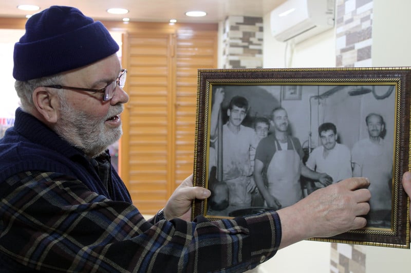 Man in wool hat looks at framed photo he is holding up