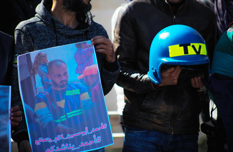 Protesters hold up a poster of Ahmad Abu Hussein and a blue helmet