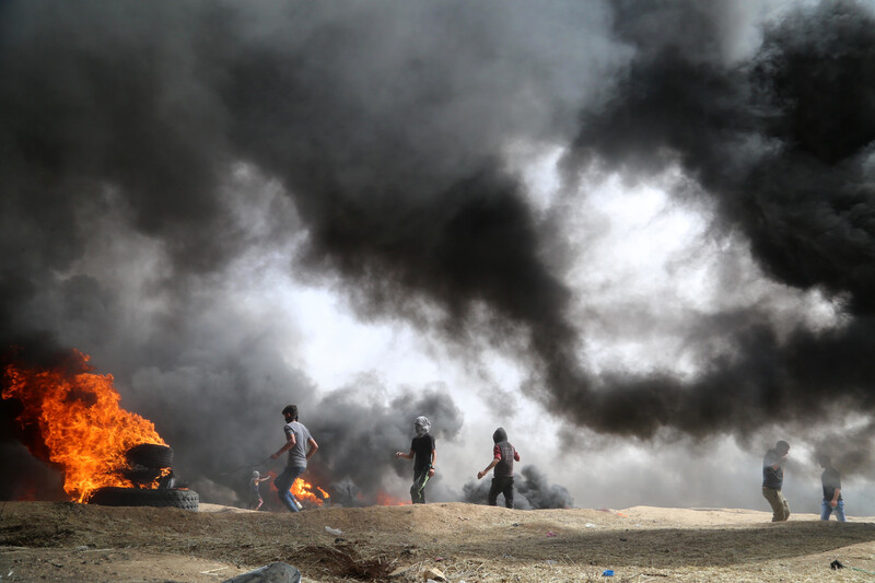 Landscape view of protesters against thick plumes of smoke from burning tires