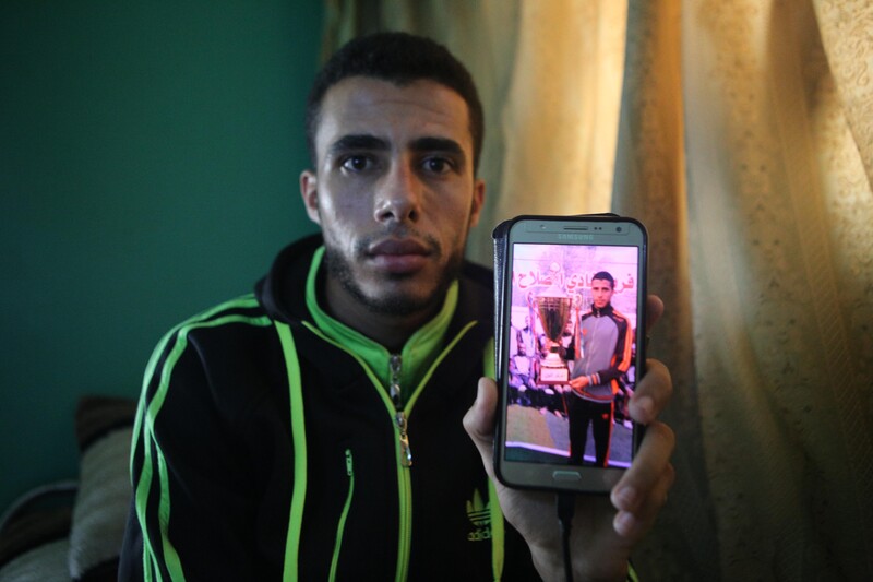 Young man in athletic wear holds up phone showing him receiving a trophy