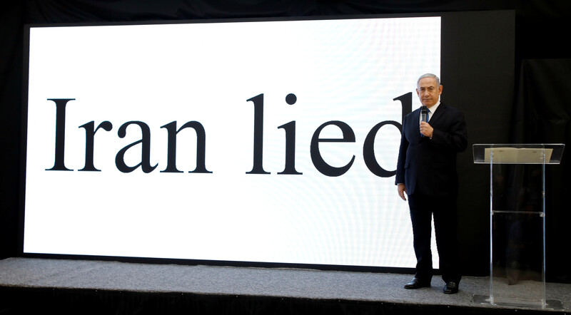 Netanyahu stands on stage with Iran lied in giant letters projected on a screen behind him