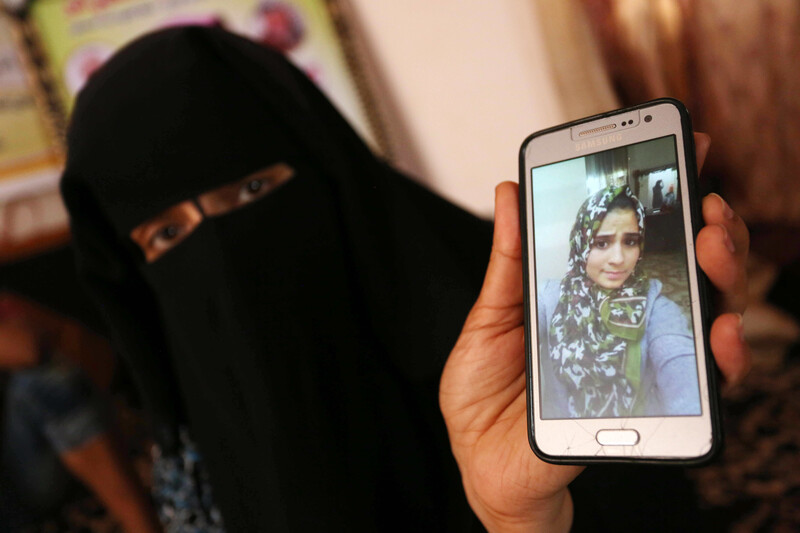 Woman wearing niqab displays photo of adolescent girl wearing a hijab on a mobile phone