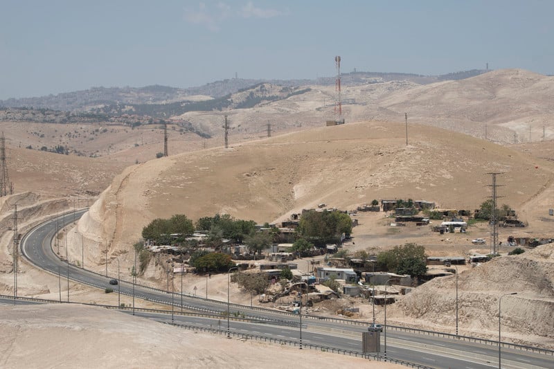 Landscape view of ramshackle village surrounded by fenced road and barren hills