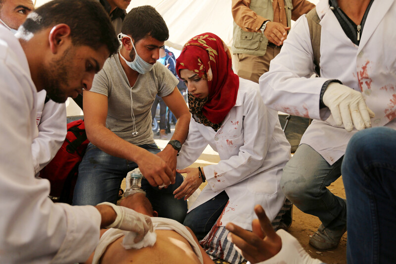 Woman surrounded by others tends to wounded person