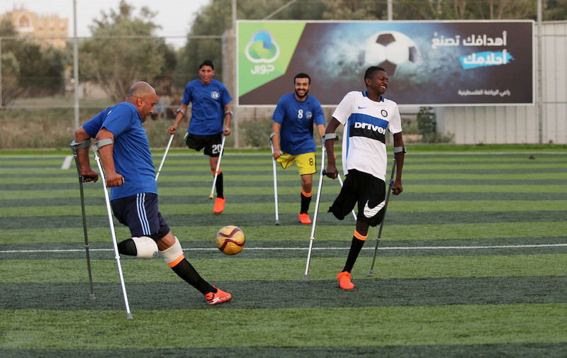 Photo shows four players using crutches competing for control of a ball on a football pitch