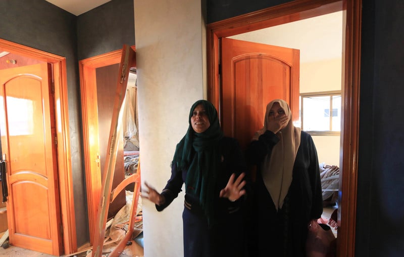 Two women react with shock in damaged home