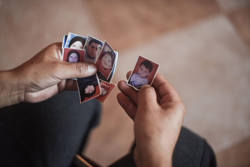 Close-up of two hands holding passport-sized portrait photos