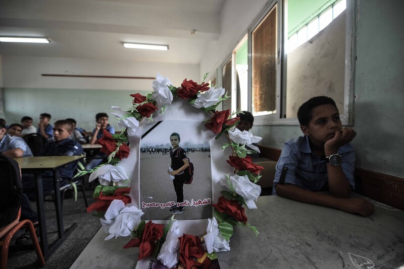 Wreathed photo of boy standing at protest sits on desk in a schoolroom with boys sitting at the desks