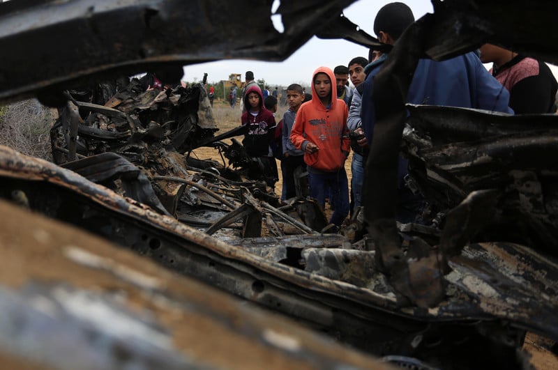 Boys look at wreckage of burned-out vehicle