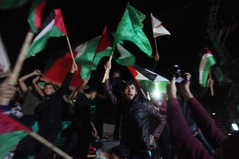 Young men wave the national flag and the Hamas flag at night