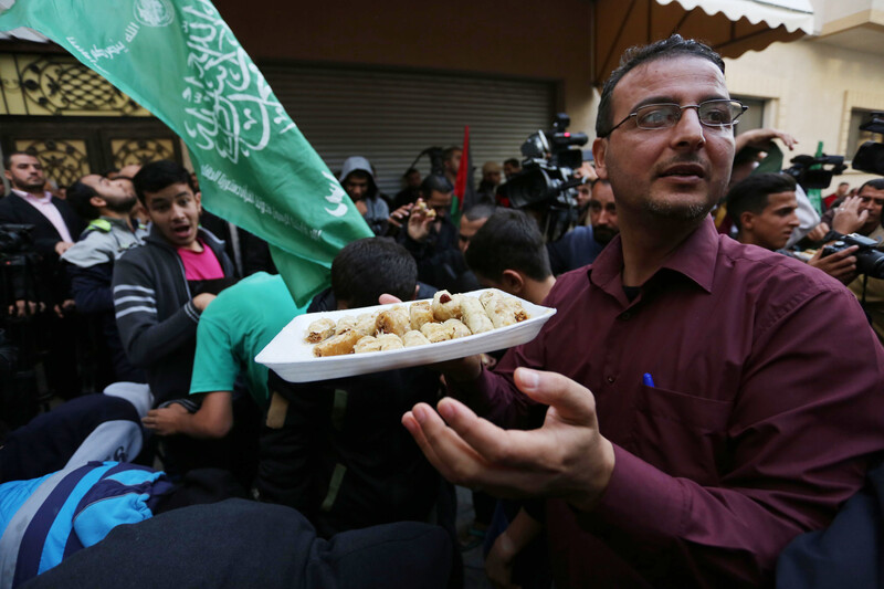 A man holds a tray of sweets amid a crowd