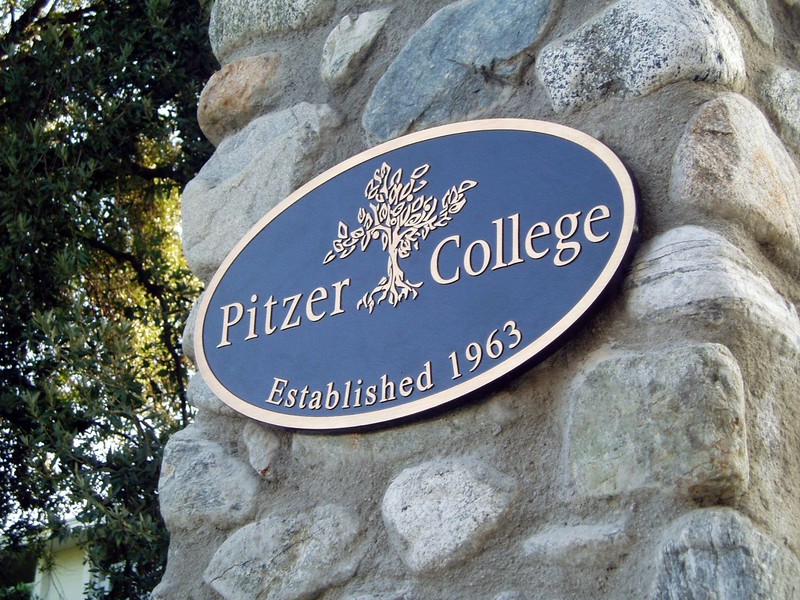 A metal placard on a stone wall says "Pitzer College, established 1963."