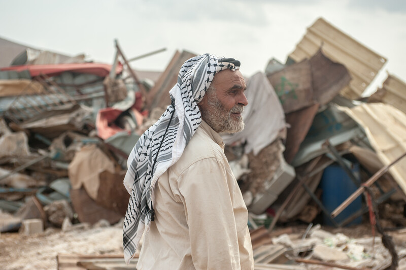 Omar Arif Bisharat stands in front of the rubble of his home in al-Hadidiya.