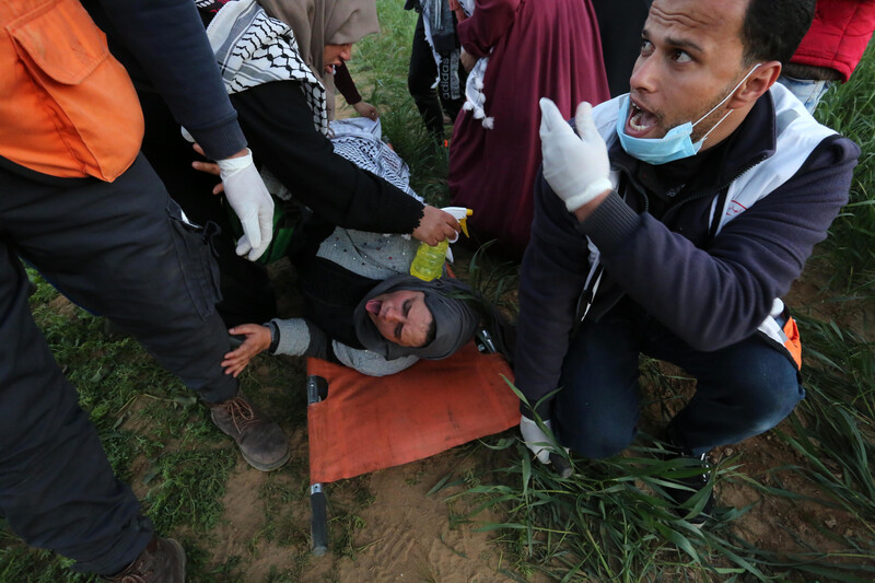 A woman on a stretcher sticks her tongue out as a woman holding a spray bottle tends to her