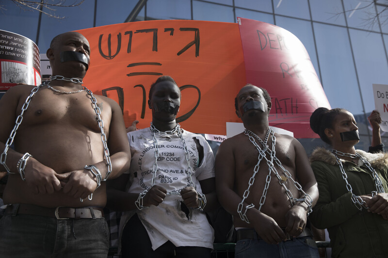 Men and women wear tape over their mouths and shackles around their writsts and necks