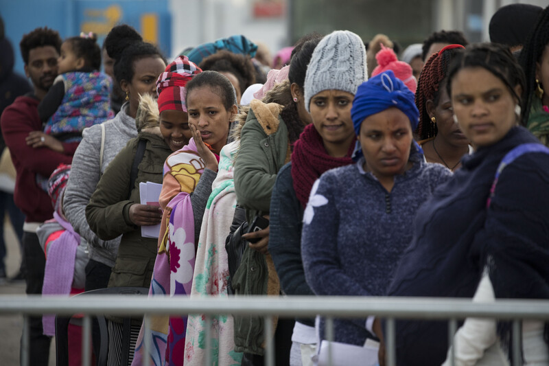 Women wearing winter clothing stand in a queue