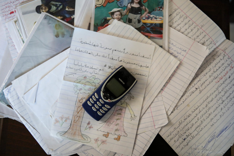 An early model Nokia phone sits on top of a pile of hand-written letters and family photos