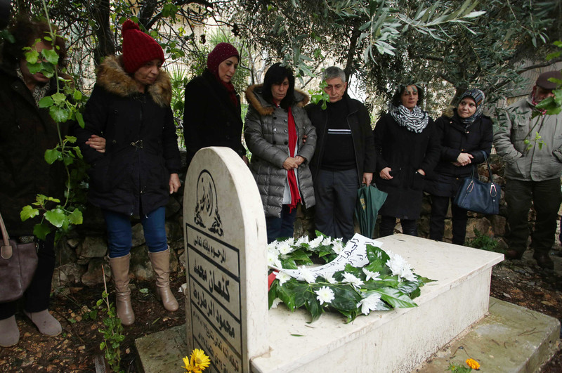 Khalida Jarrar stands near her father's tombstone with others. 