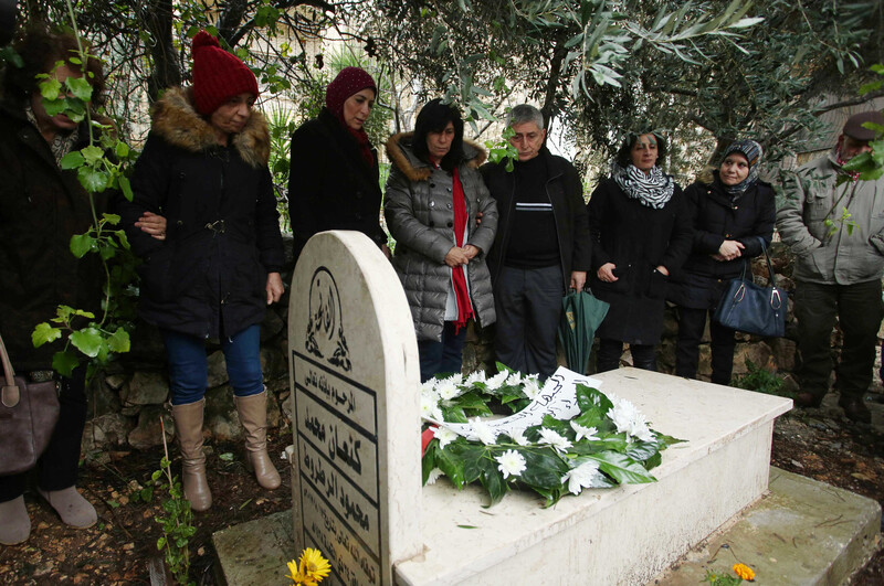Khalida Jarrar stands near her father's tombstone with others.
