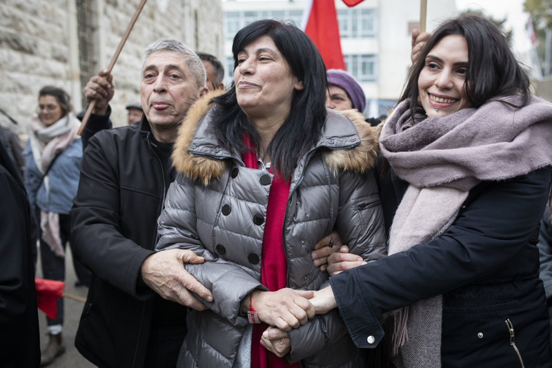 Flanked by her husband and daughter, Khalida Jarrar smiles as she and wellsihers celebrate her release
