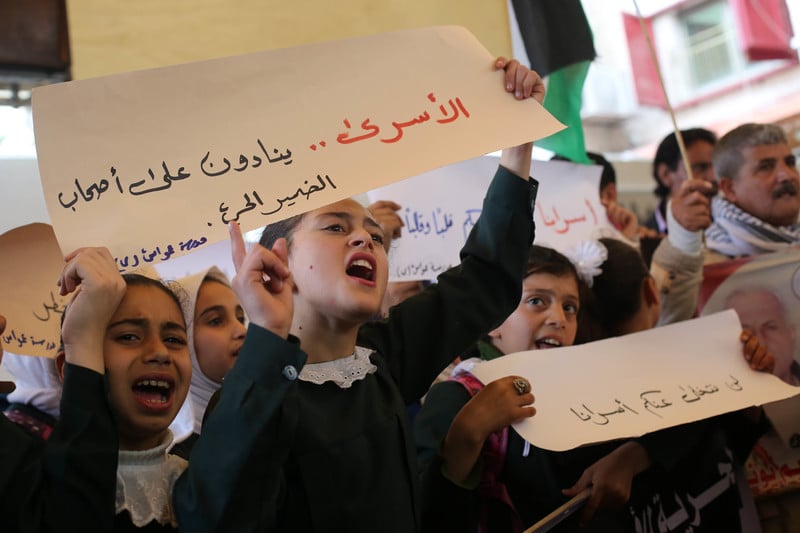Palestinian children, adults hold banners. 
