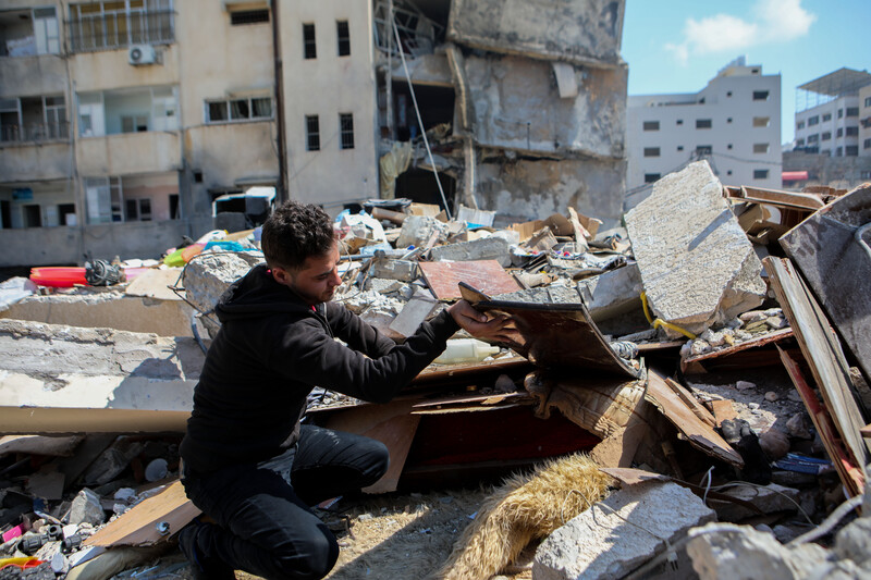 Walid al-Shawa searches the flattened remains of his apartment complex. Man combs through rubble